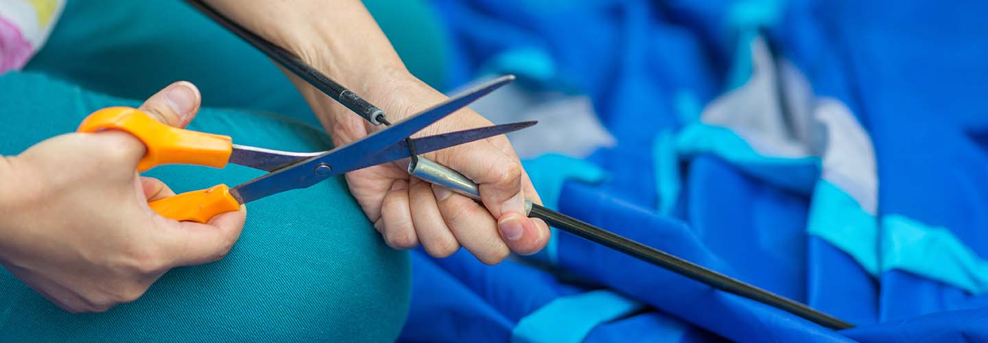 A person holding scissors cutting a thread.