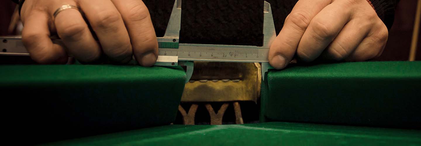 A close-up view of a pool table with green felt being measured for refelting.