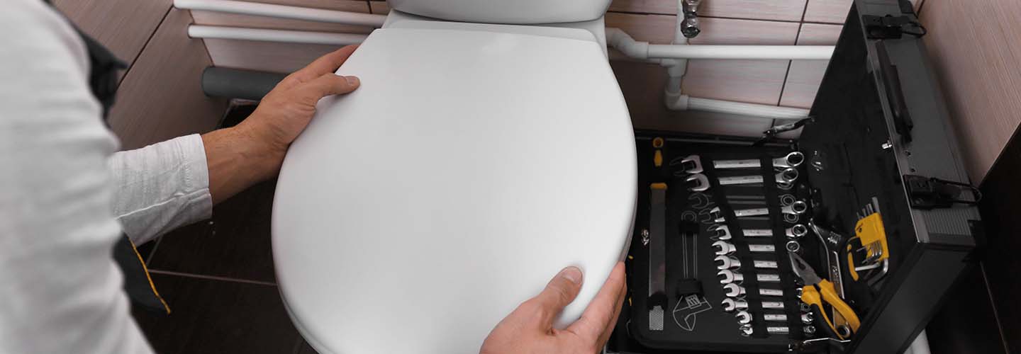 A person installing a toilet seat in a bathroom.