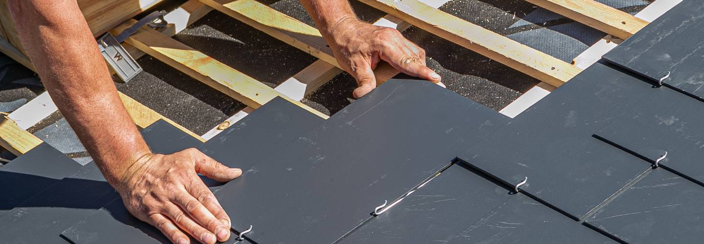 A close-up view of a beautiful slate roof with various shades of gray tiles neatly arranged in a pattern.