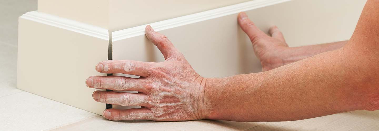 A close-up photo of white baseboards against a light gray wall, showcasing their clean lines and smooth finish.