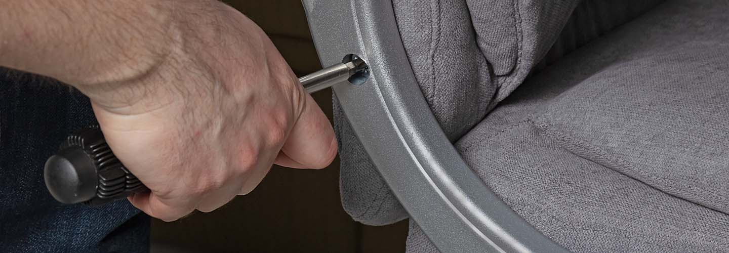 A person tightening a screw on a chair.