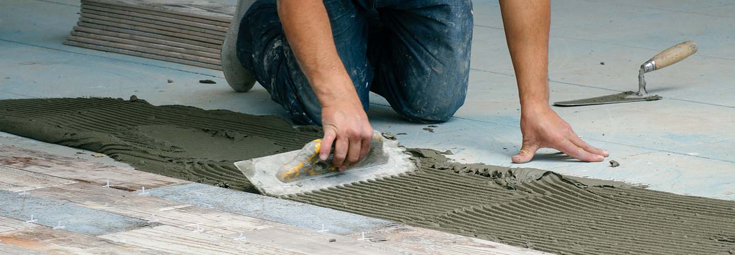 Working installing floor tiles, using tile adhesive.