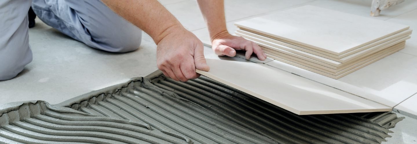 A close-up view of a person installing porcelain tiles on a floor.