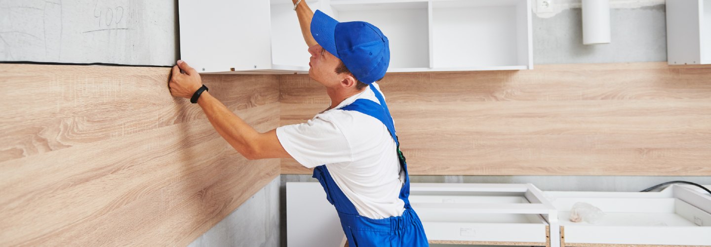 A person installing sleek white cabinets for a new kitchen.