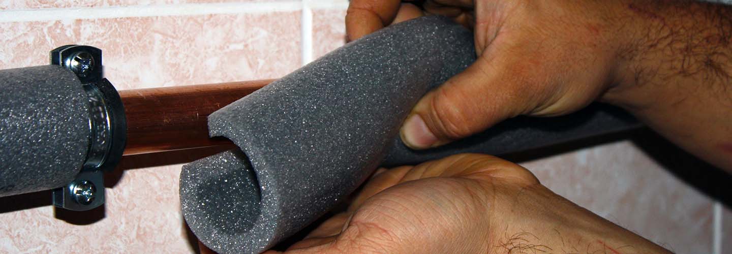 A close-up image of pipe insulation, showing the textured surface and the protective layer surrounding the pipe.