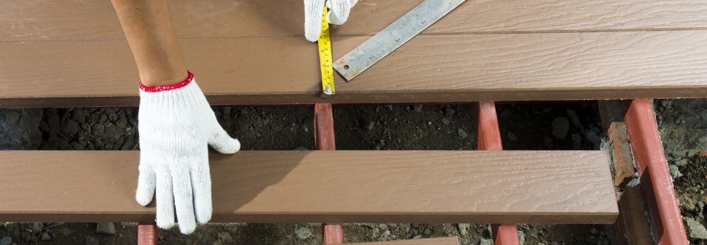 A close up photo of a hand arranging planks for a patio.