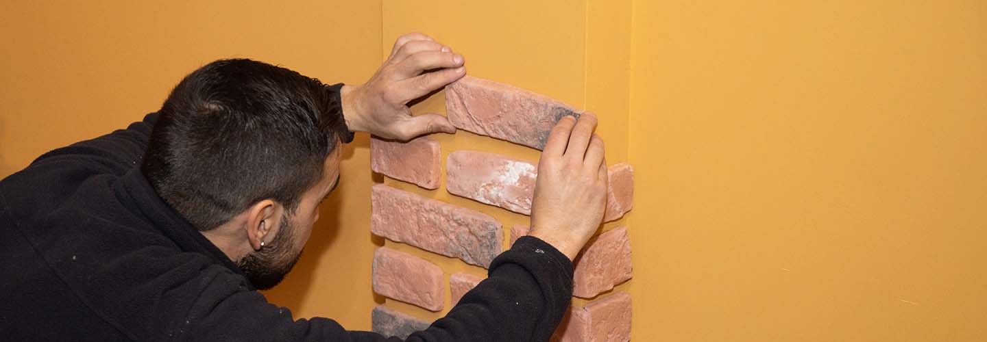 Working installing brick tiles on a wall.