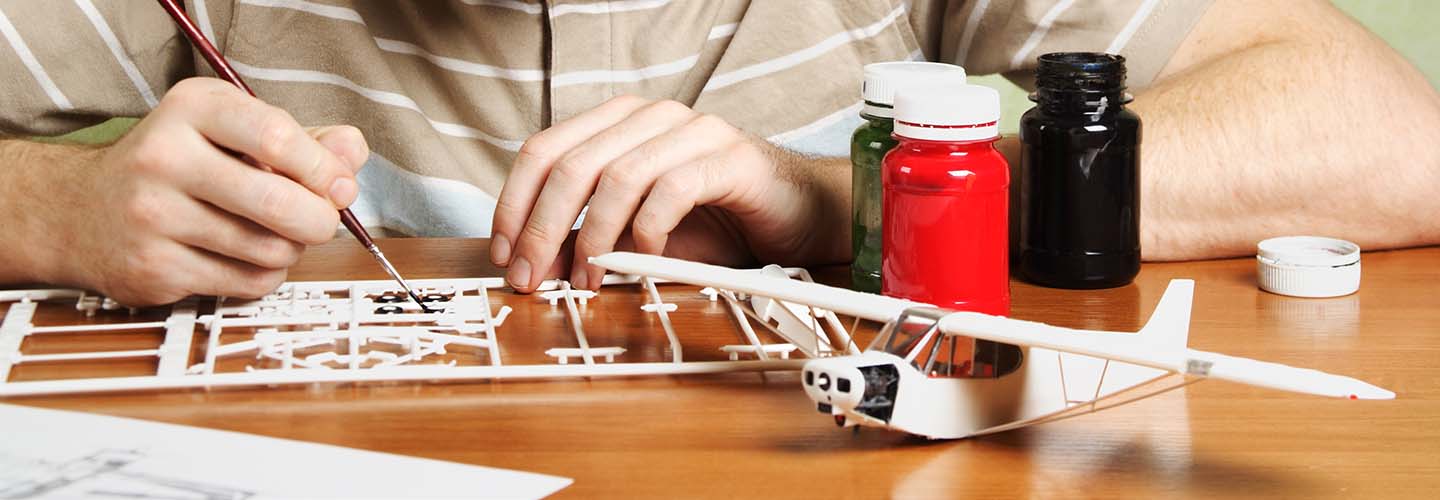 A person assembling a toy, with various parts and tools spread out on a table.