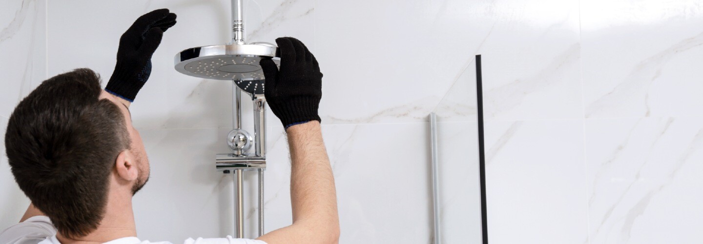 A plumber fixing a leaking shower, with tools and equipment nearby.