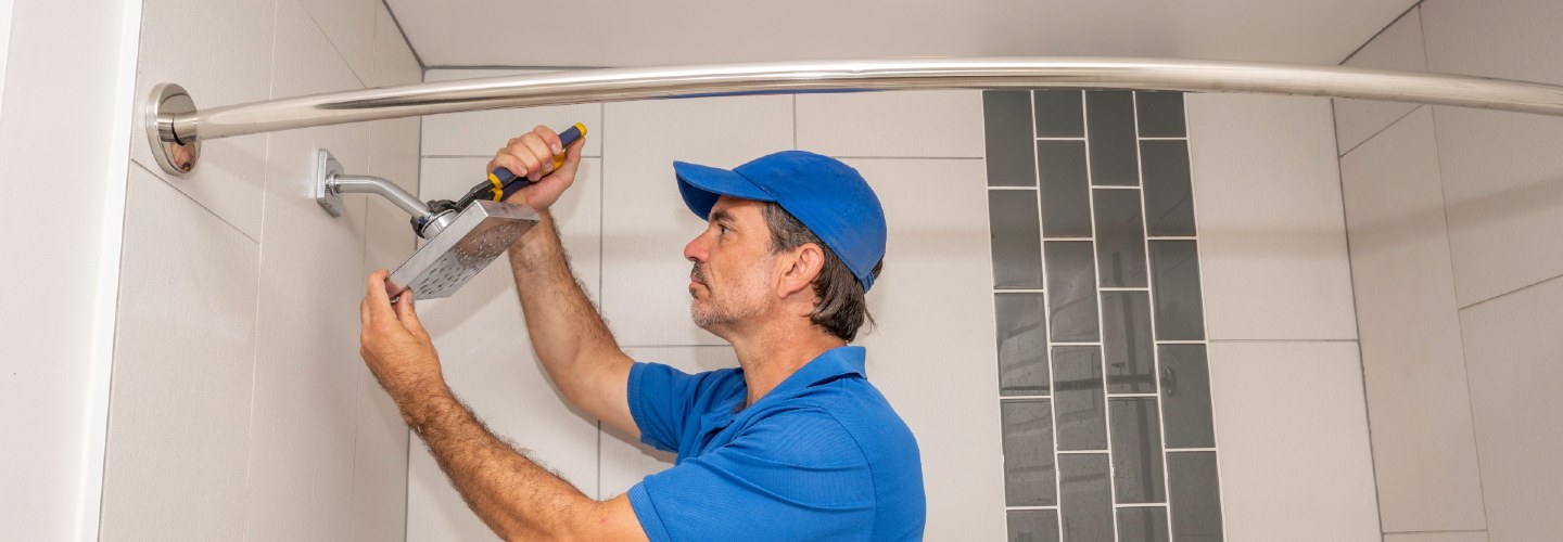 A close-up of a person installing a shower head onto a bathroom wall.