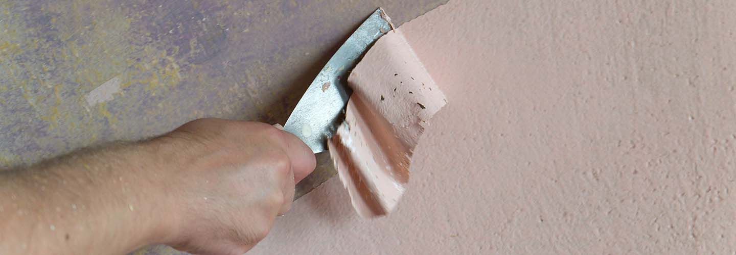 A person using a paint stripper to remove old paint from a wooden surface.