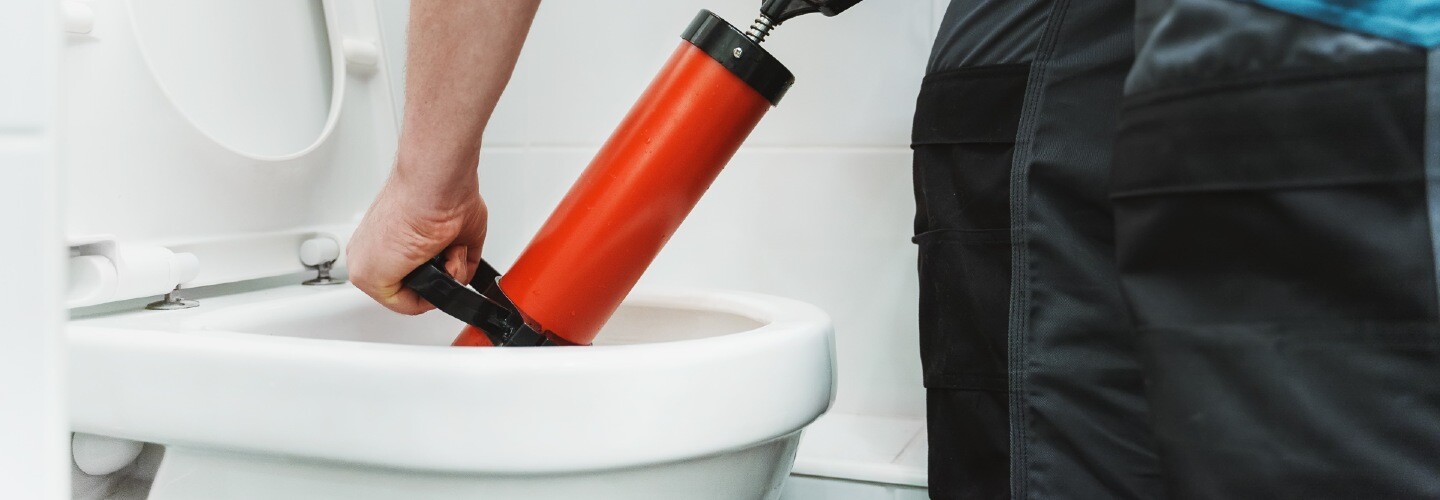 A person using a plunger to unclog a toilet.