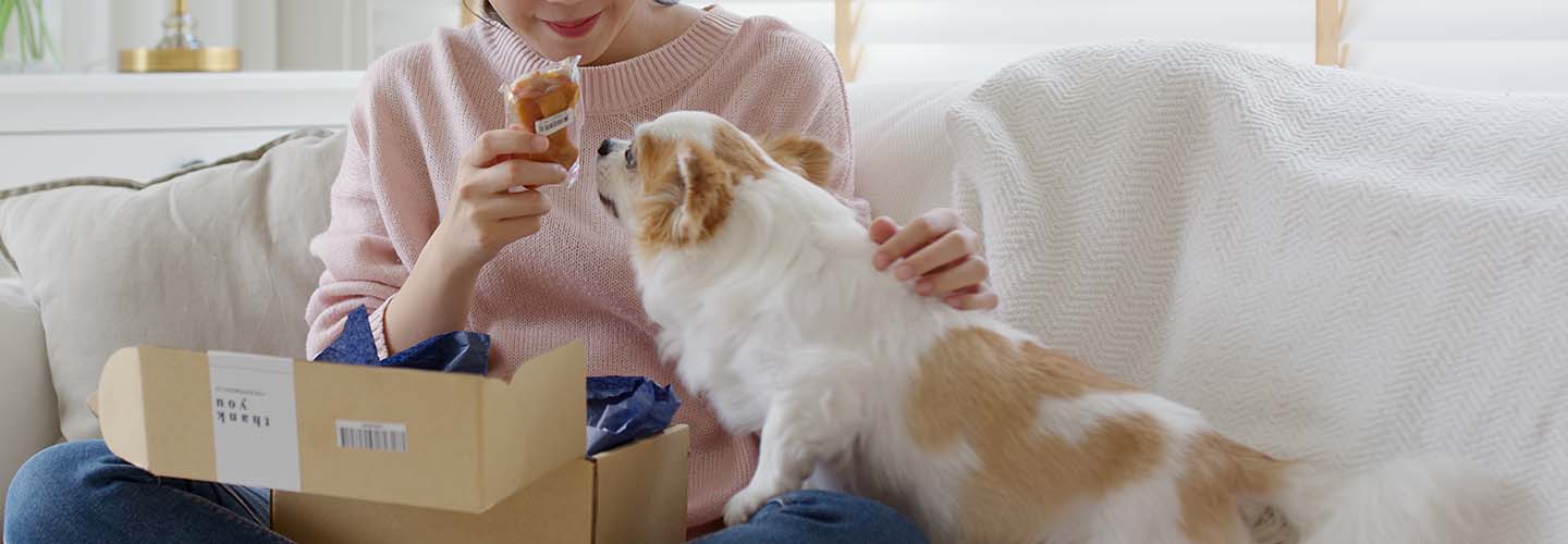 A close-up of a dog and pet owner with some pet food that was delivered in a parcel.