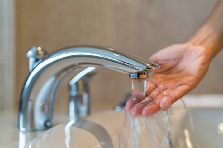 touching water from faucet to check temperature