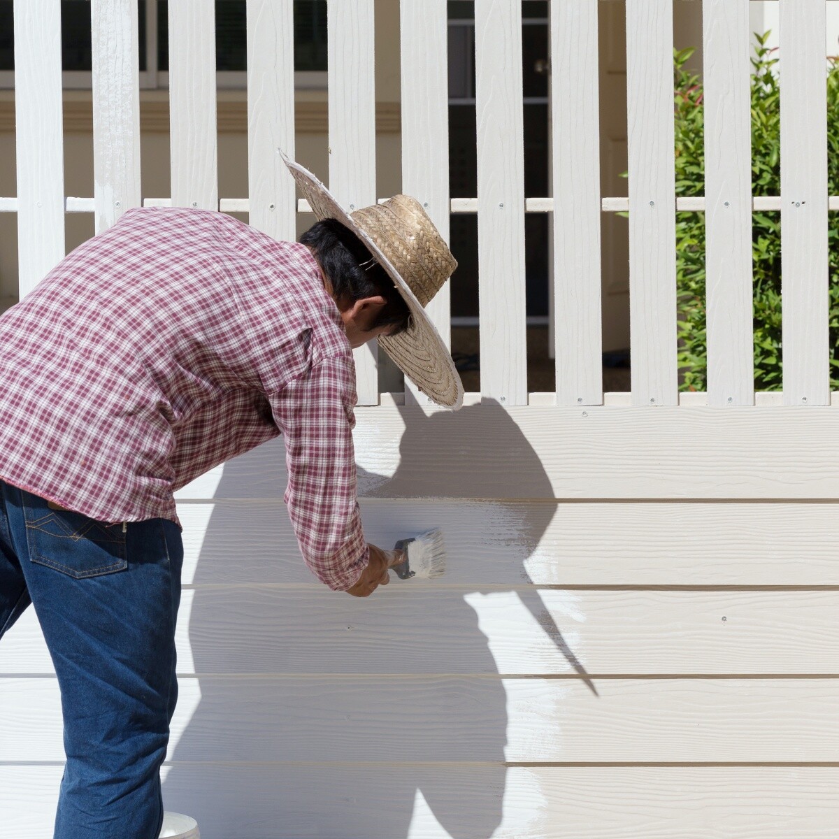 a man painting a fence with white paint