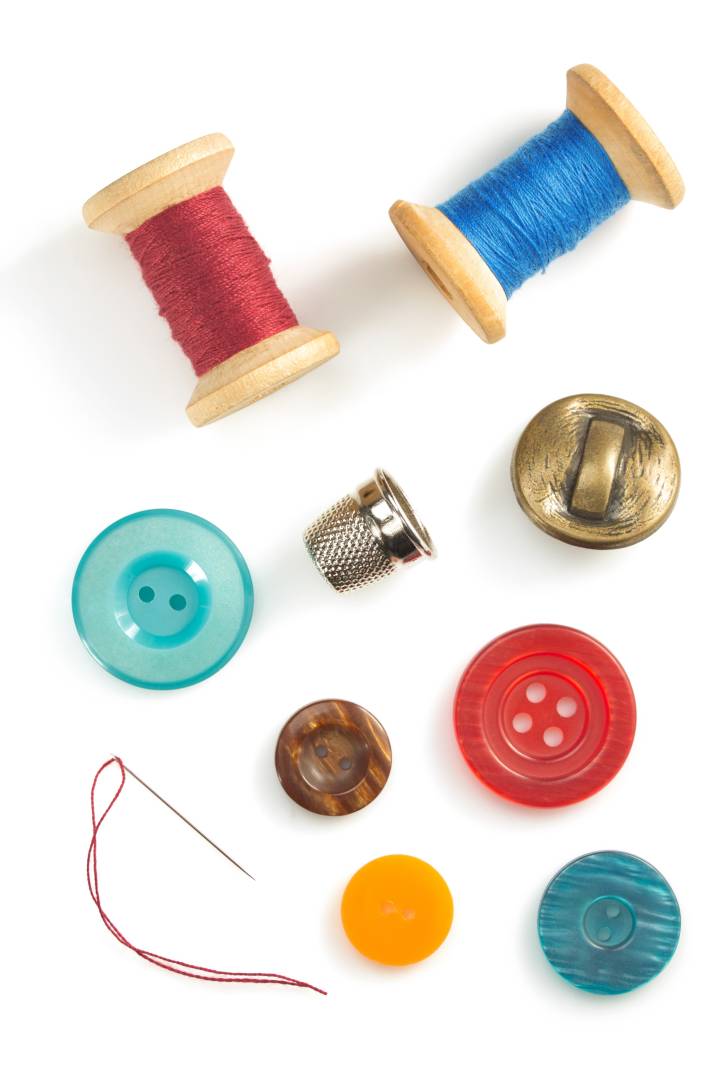a collection of sewing materials, including red and blue buttons and thread