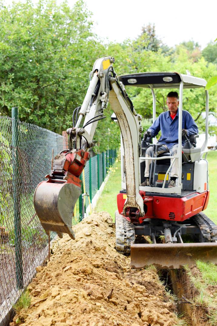 a man using a mini digger in a garden