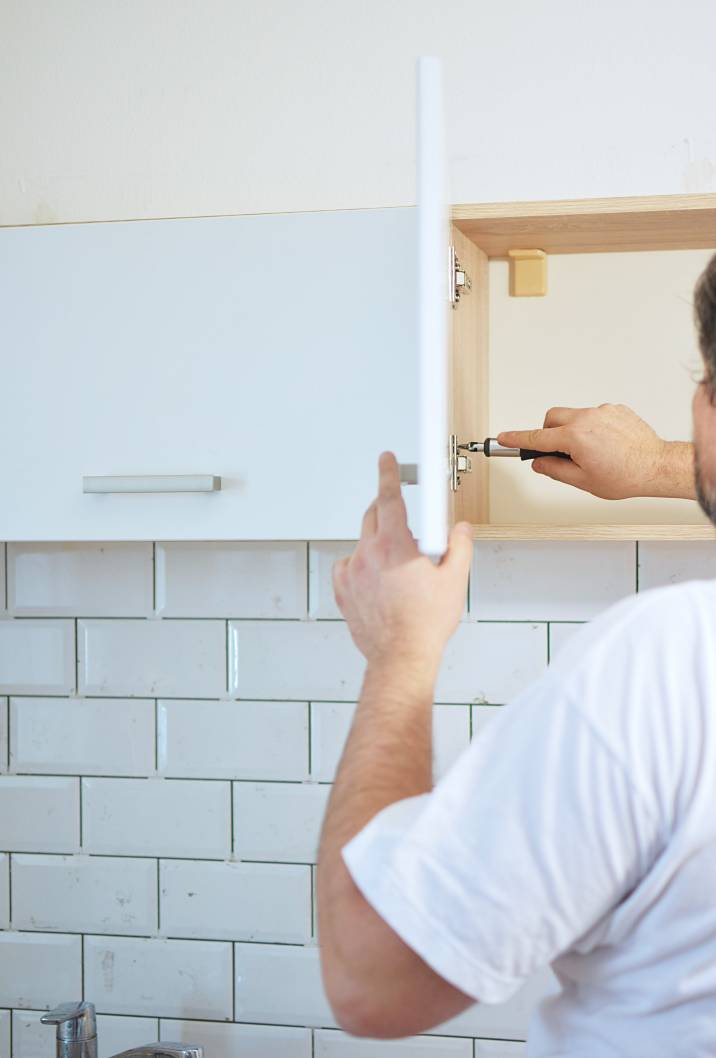 a man tightening the brackets of a kitchen cabinet door