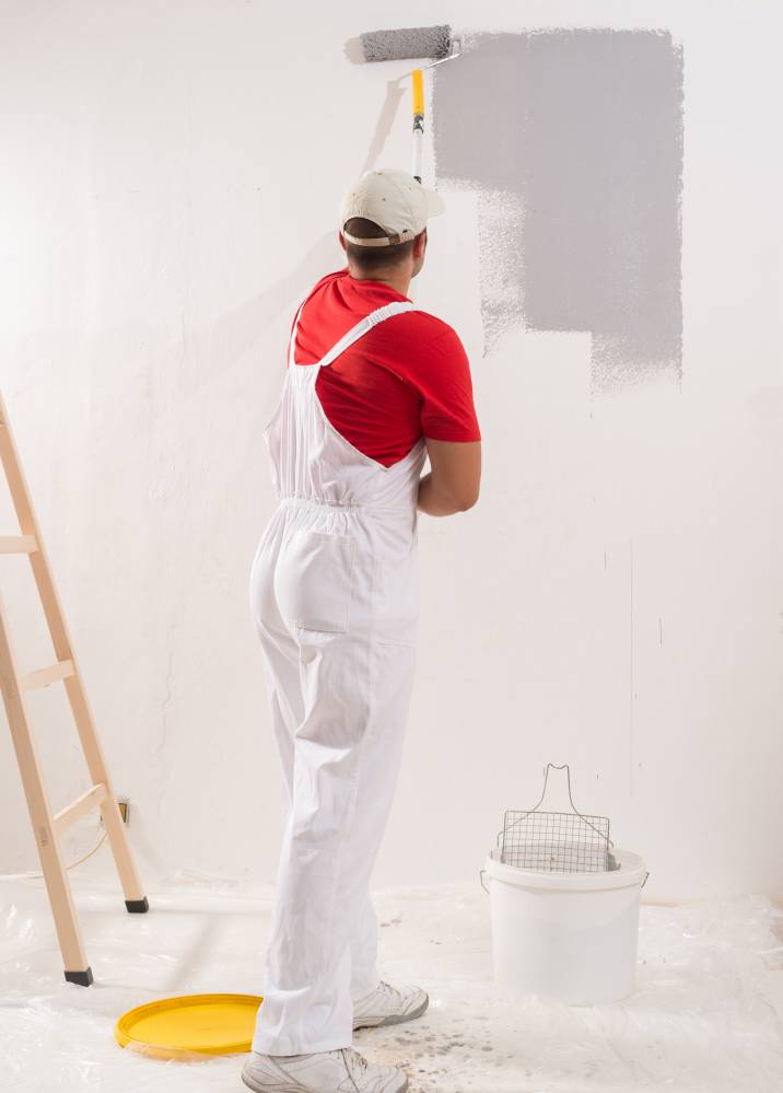 a uniformed man painting a wall