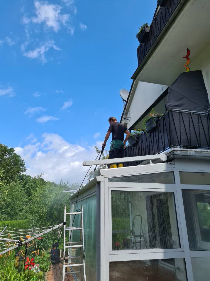 a handyman cleaning the roof of a sunroom