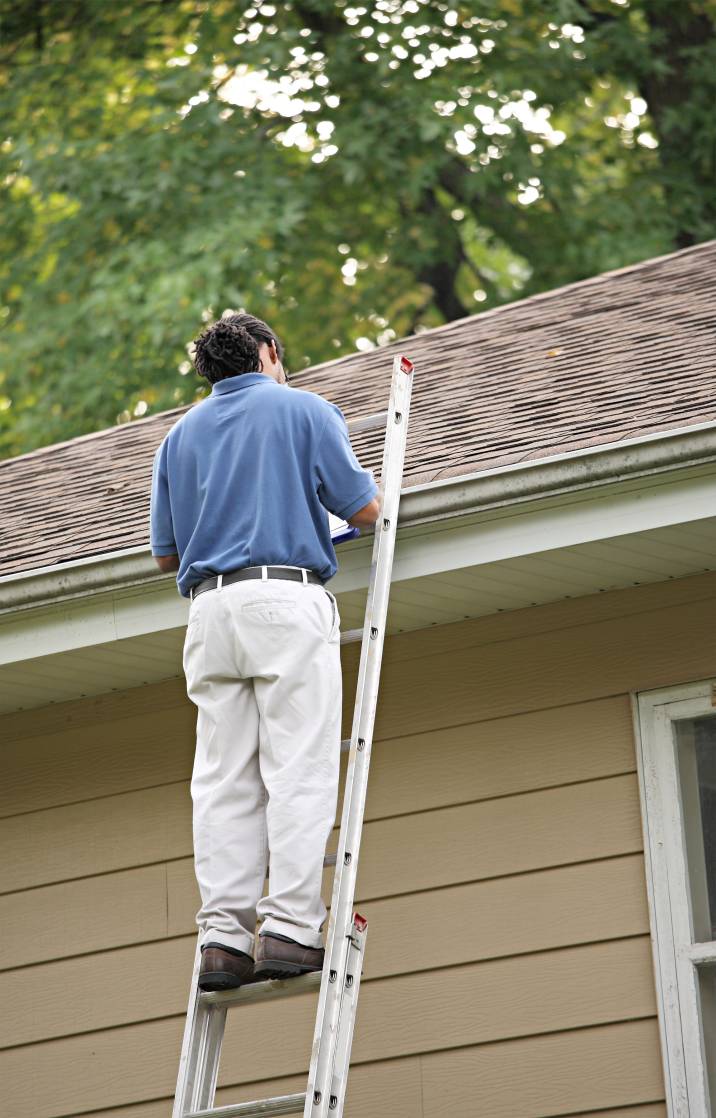 a man inspecting a roof for hail damage