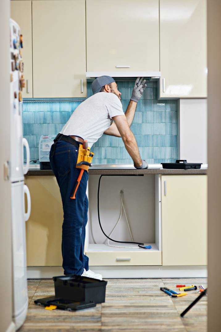 a handyman inspecting a kitchen exhaust fan