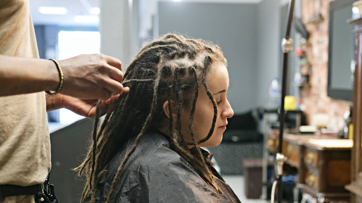 A professional hairstylist creates neat and well-sectioned dreadlocks for a client at a salon.