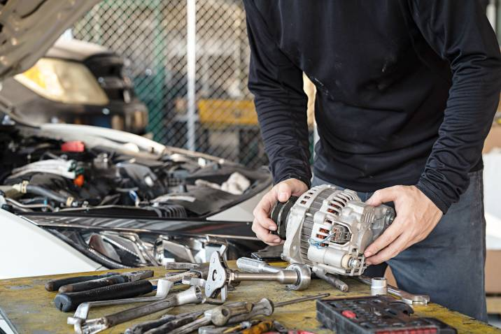 a man holding a car alternator