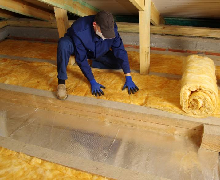 a worker using mineral wool to insulate the attic