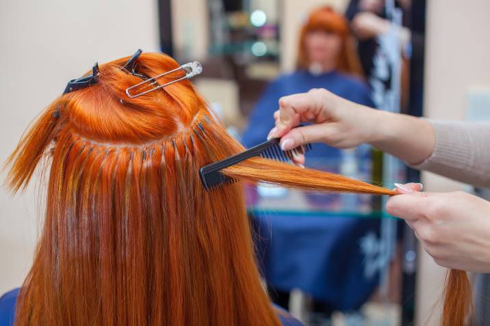 a woman with red hair getting hair extensions