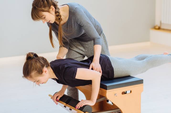 a Pilates instructor guiding a student to perform a move