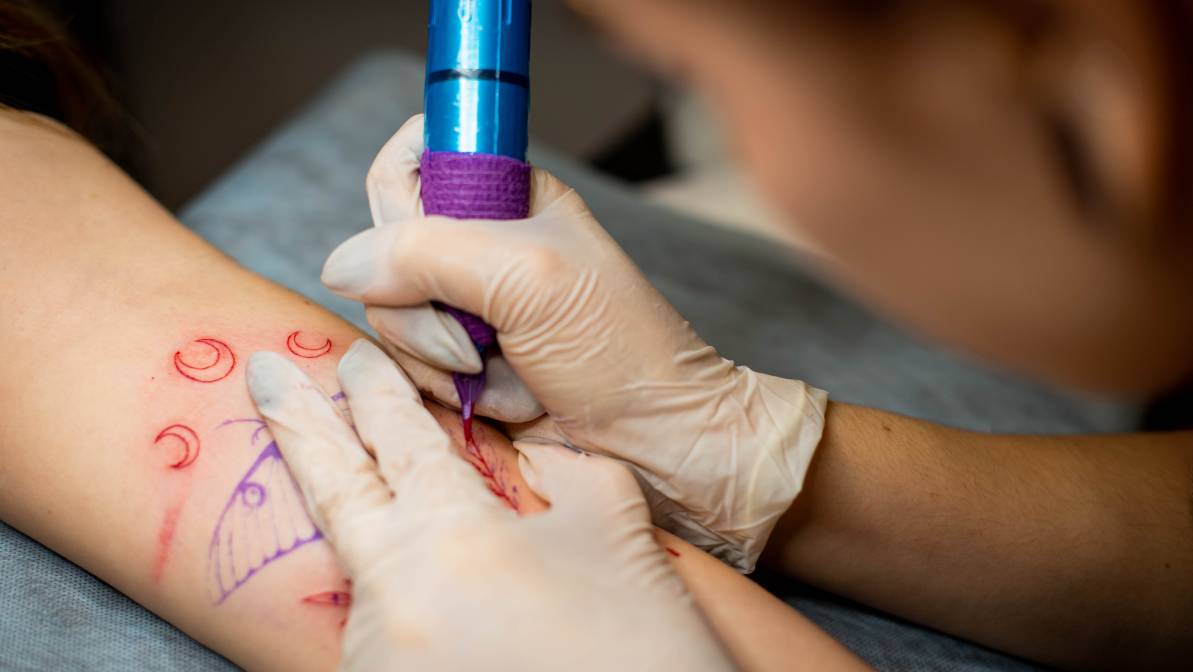 tattoo artist using machine gun tattoo a client