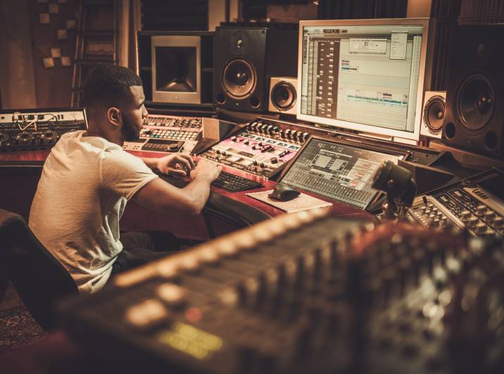 male sound engineer working at mixing panel in boutique recording studio