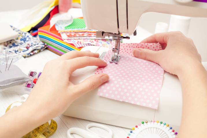 Sewing pink polka dot fabric on machine