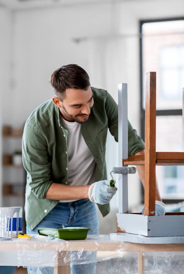 painting blue-collar job, man painting chair with brush roller