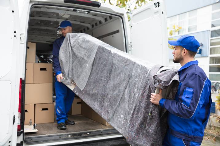 two young delivery men unloading furniture from moving van