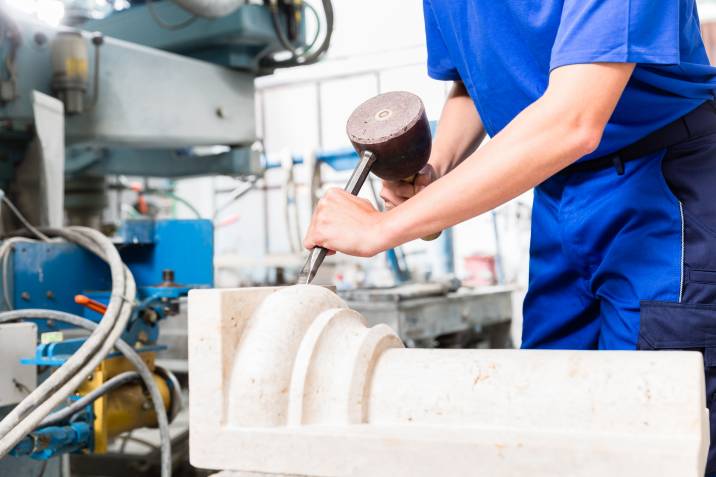 tradesperson, woman stonemason carving pillar out of stone in her workshop