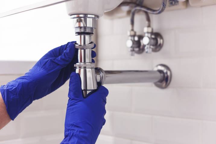 plumber repairing chrome siphon under sink