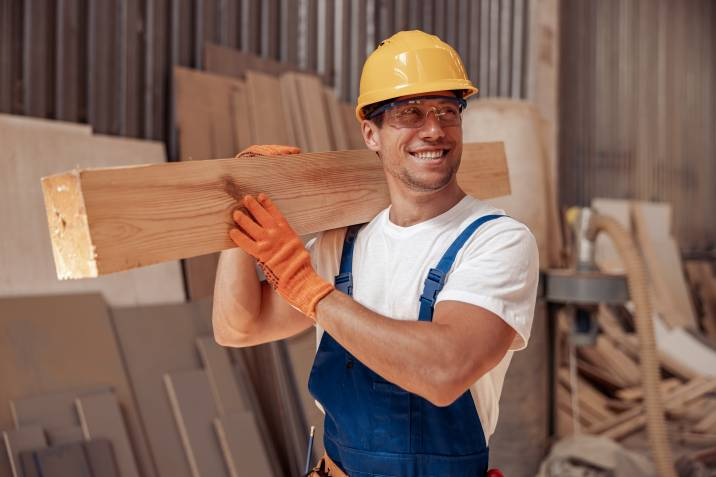 handyman lifting large wood planks