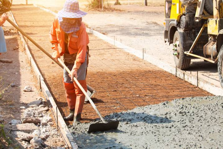 general laborer smoothing concrete on roadside repair project
