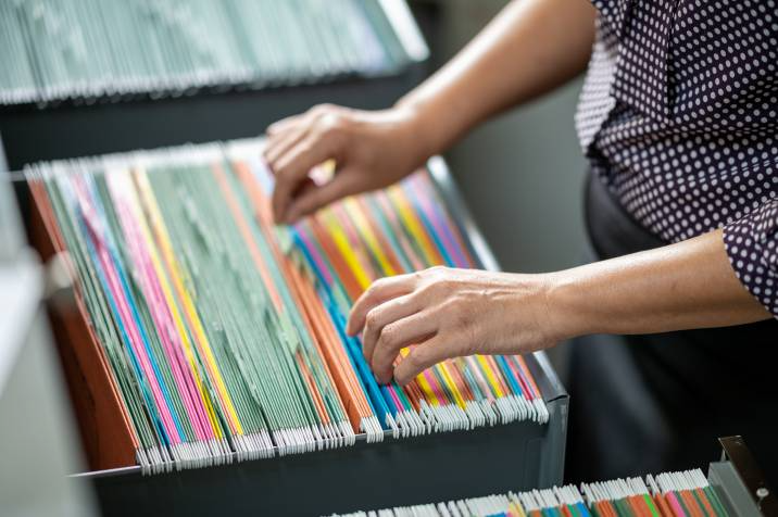 admin sorting through color coded files in a drawer