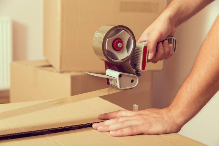 man sealing boxes with packing tape