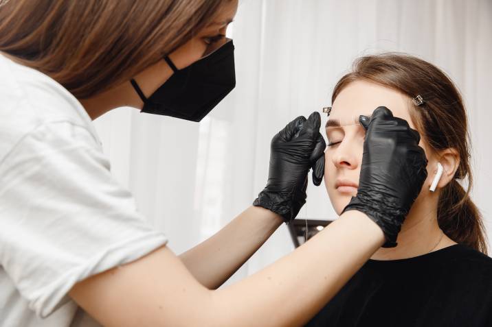a beautician threading a woman's eyebrows