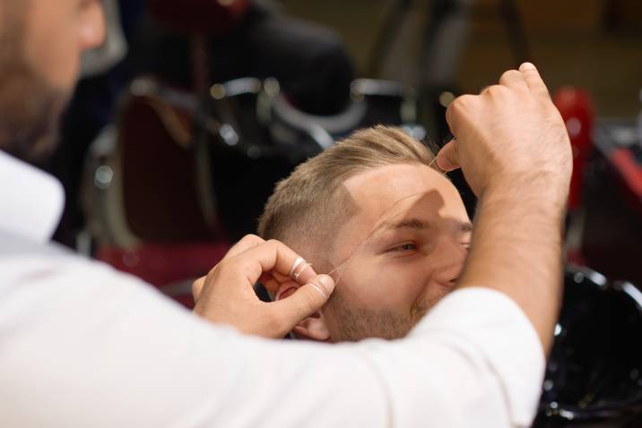 a beautician threading a man's eyebrows