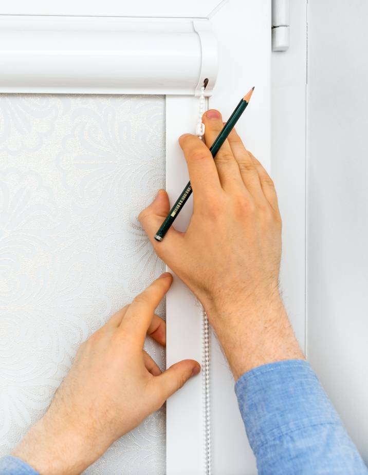 a man measuring a window frame before installing blinds