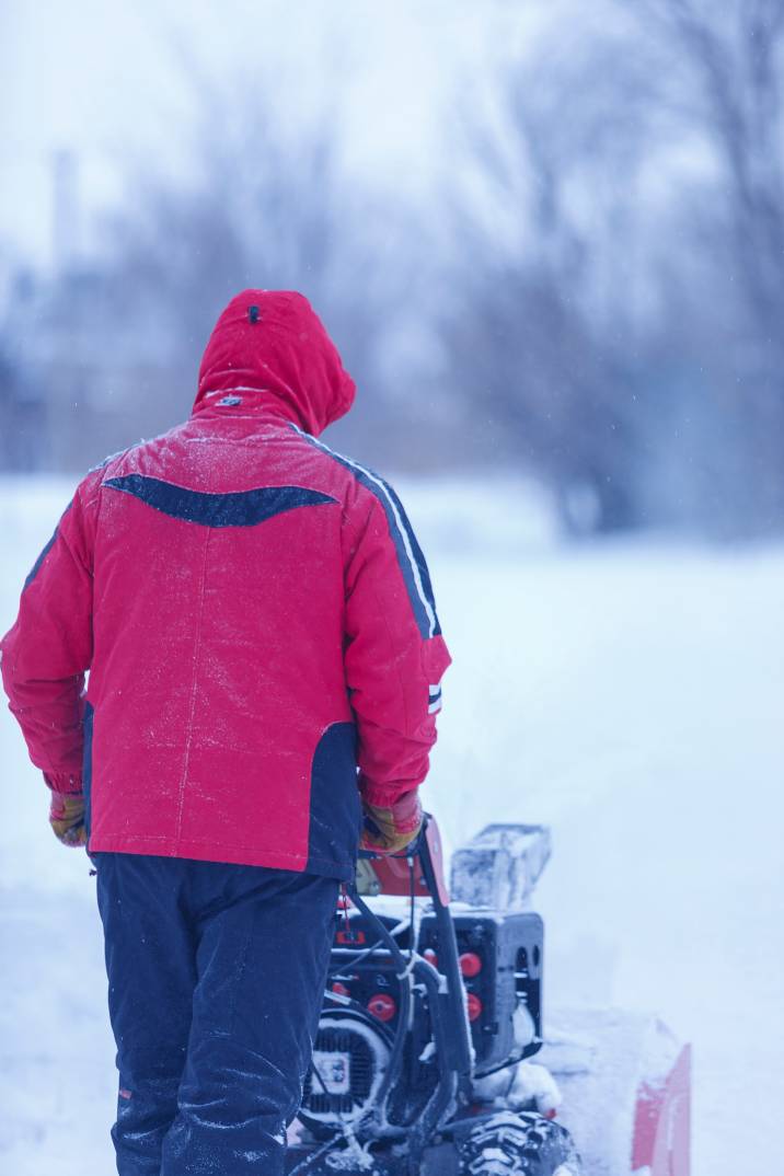 a man in a red jacket plowing snow