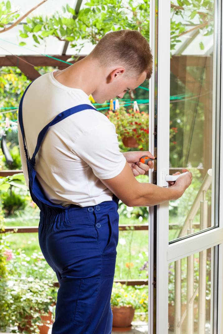 a handyman weather-stripping a window