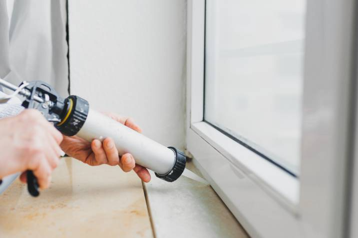 person applying weatherstripping material onto a window