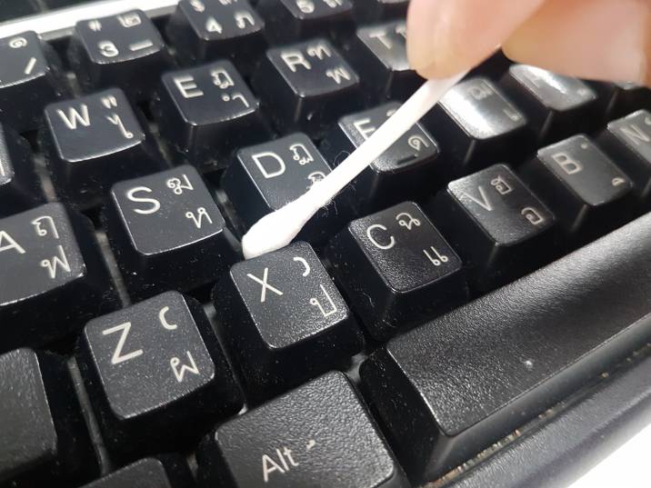 removing dust from external keyboard with cotton swab